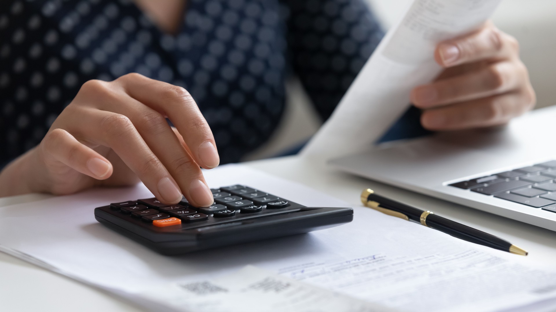 Close up woman calculating finances, using calculator and laptop